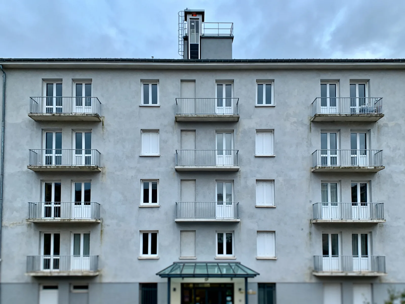Façade d'un immeuble résidentiel de quatre étages avec sa machinerie d'ascenseur en toiture